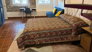 Een slaapkamer met een bed met een decoratieve spreidek, een bureau en een stoel.
