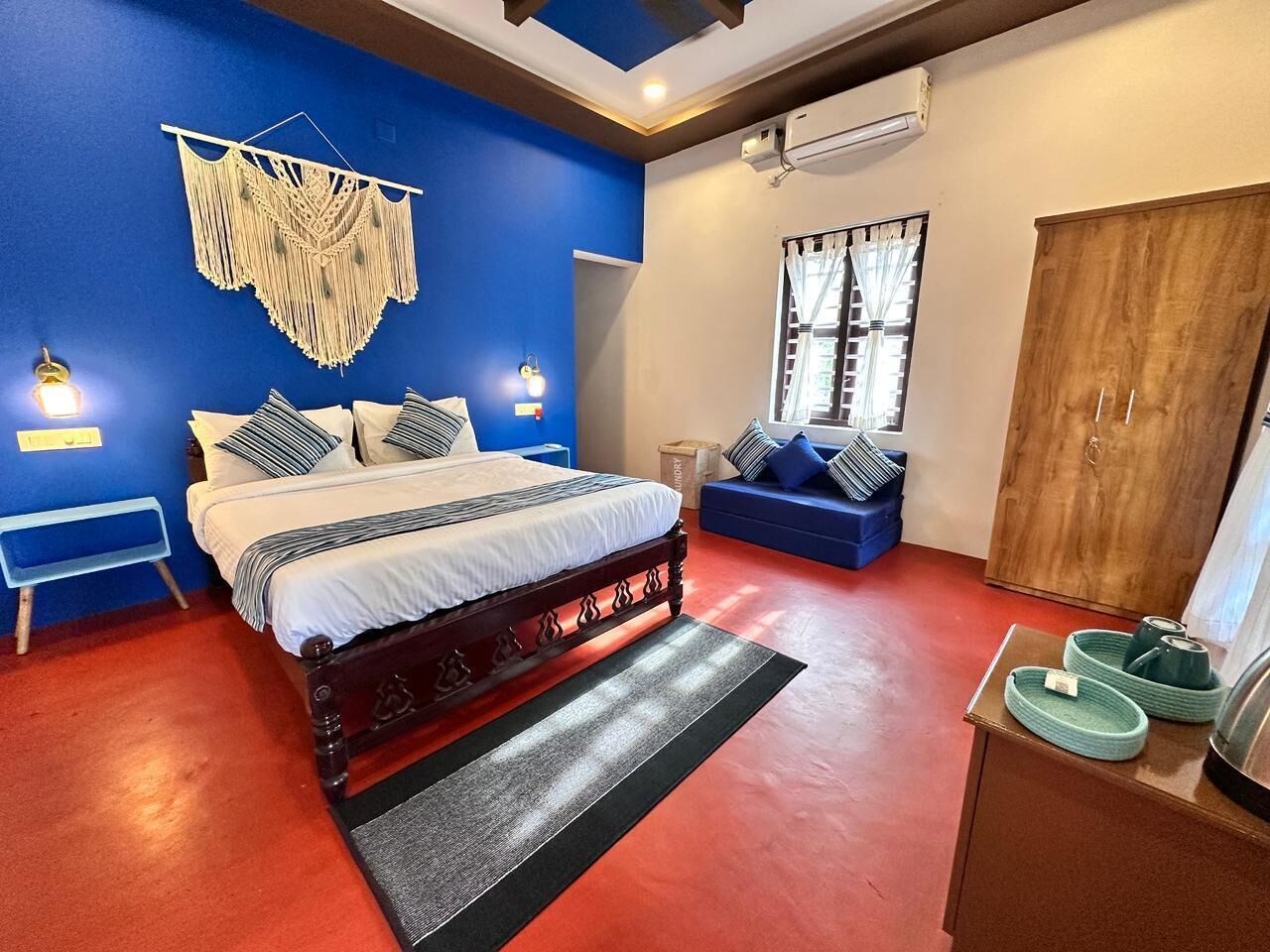 Un dormitorio con cama, pared azul, armario de madera y sofá azul.