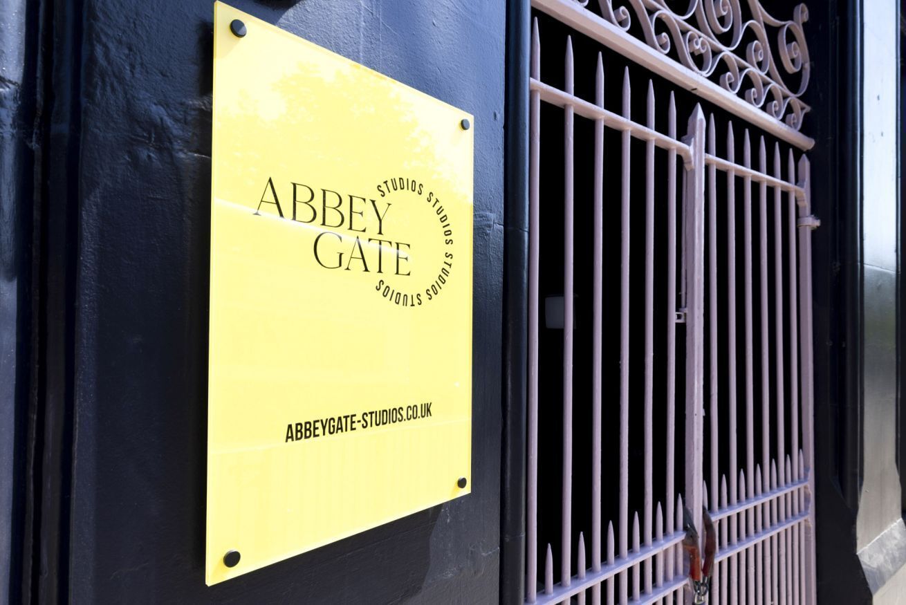 Uma placa amarela com 'Abbey Gate Studios' e um endereço de site.