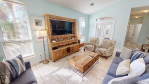 A living room with a wooden entertainment center, two armchairs, a coffee table, and a TV. - Mango Tango - Dog Friendly 5 BR home in gated community close to beach (Miramar Beach)
