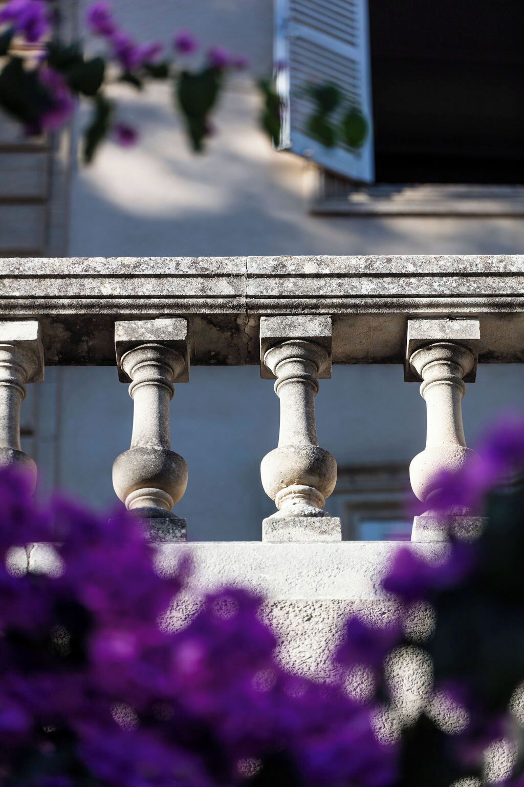 A stone balustrade with a classical design, overlooking a building with a sign.