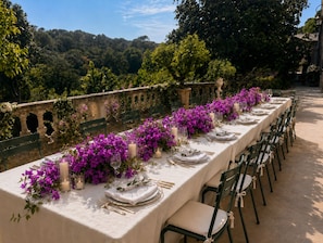 Mesa de comedor al aire libre con sillas, rodeada de vistas a un jardín.