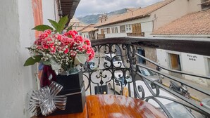 Une table en bois sur laquelle est posé un vase de fleurs, sur un balcon doté d’une rambarde en métal.