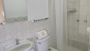 Une salle de bain avec des toilettes, un lavabo et une douche.
