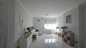 A modern living room with a white sofa, a wooden sideboard, a large window with curtains, and a ceiling fan. - Casa Adelaide close to MM3 Family sized new apartment (Milano)