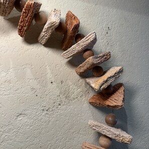 A textured wall with a wooden object hanging on it. - Zoe Pousada (Ipojuca)