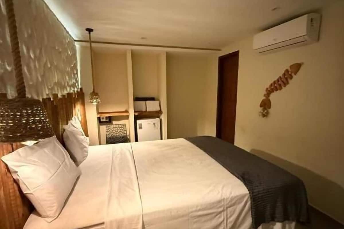 Ein Schlafzimmer mit einem Bett, Nachttischen, einer Hängeleuchte und einer Klimaanlage an der Wand.