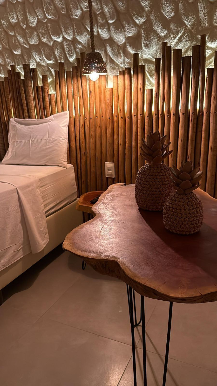 Um quarto com uma cama, uma mesa de madeira e uma parede com ripas verticais.