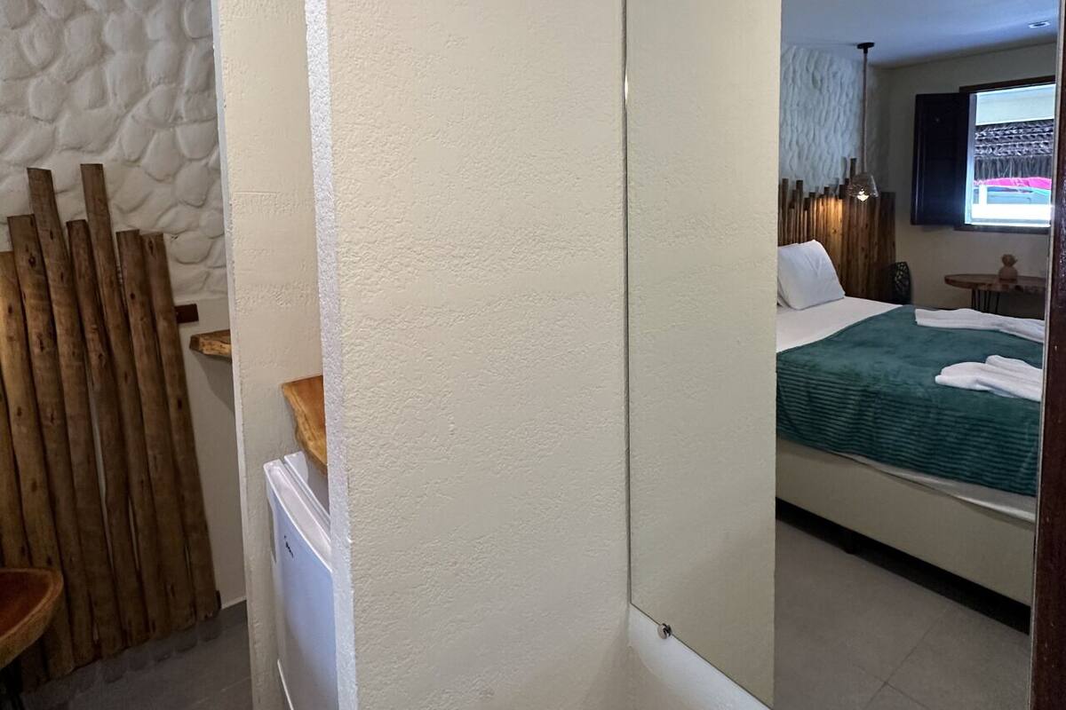 Ein Hotelzimmer mit einem Bett, einer Holzwand und einem Spiegel, der den Raum widerspiegelt.