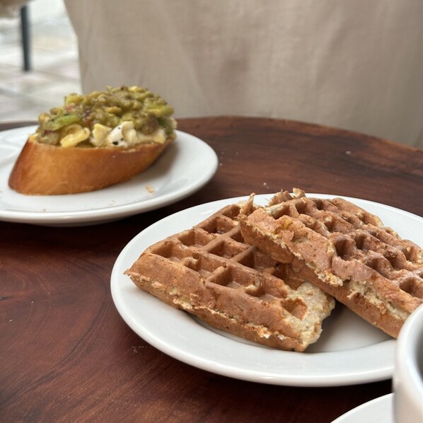 A table with waffles and a sandwich. - Zoe Pousada (Ipojuca)