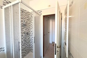 Een douche, een bidet, handdoeken, toiletpapier