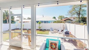 Een overdekt terras met uitzicht op een achtertuin, een barbecue en tuinmeubilair.