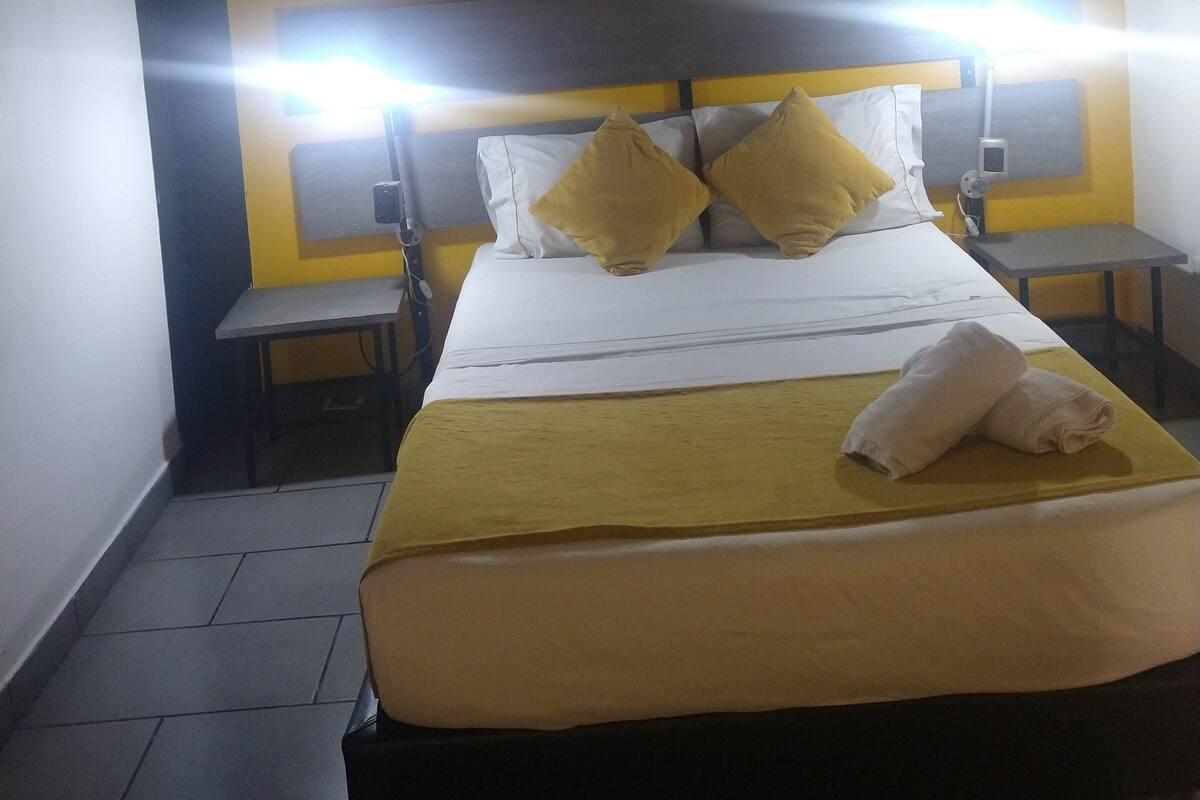 Une chambre d’hôtel avec un lit, deux tables de chevet et une petite table d’appoint.