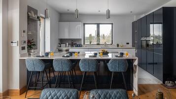 A modern kitchen with a central island, bar stools, and a dining area with a table and chairs.