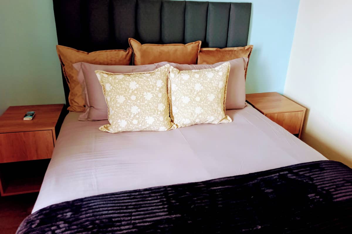A neatly made bed with a headboard, two nightstands, and a bedside table.