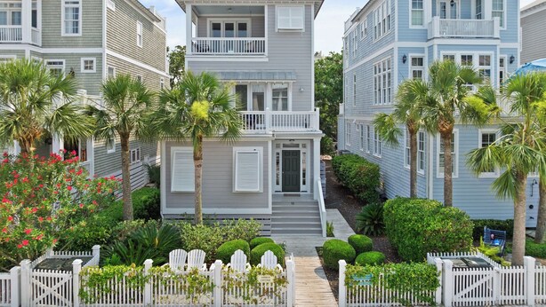 A row of coastal-style houses with a central entrance, surrounded by lush greenery and palm trees. - New Listing!  -Satilla Cottage -Coast Cottages (St Simons Island)