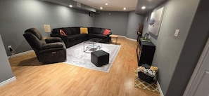 Una sala de estar moderna con un sofá seccional, un sillón reclinable, una mesa de centro y una mesita auxiliar.