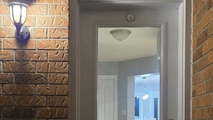 A white door with a peephole, a keypad lock, and a small step leading up to it.