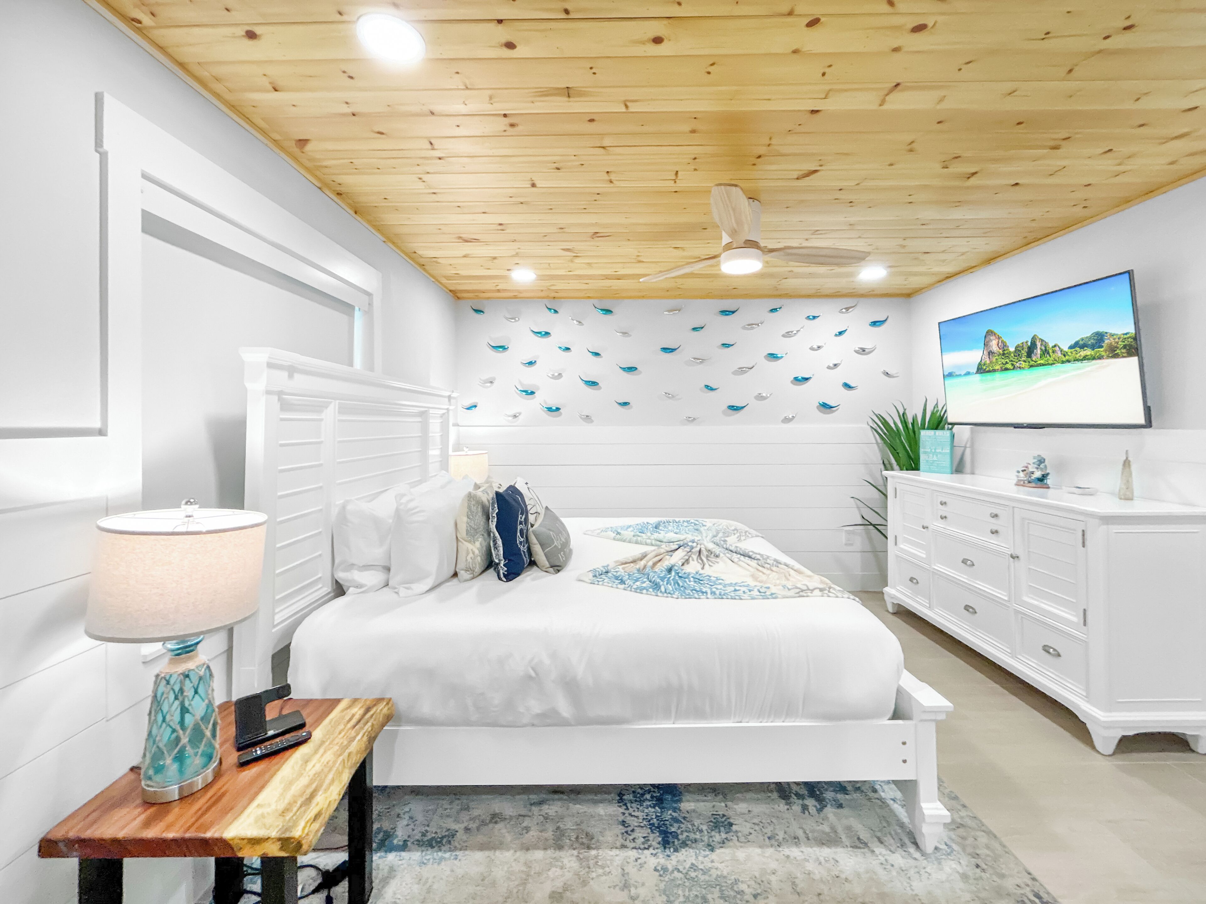 Un dormitorio con cama, mesita de noche, lámpara, cómoda y ventilador de techo.
