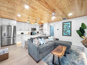A modern kitchen with stainless steel appliances, a grey sofa with patterned cushions, and a wooden coffee table. - Perfect Beach Escape - Charming 1 Bedroom Condo Just Steps From The Sand (Bradenton Beach)