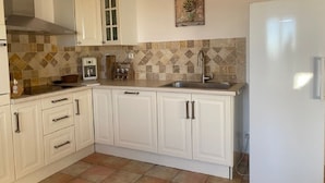 A kitchen with white cabinets, a tiled backsplash, a stainless steel sink, and a white refrigerator.