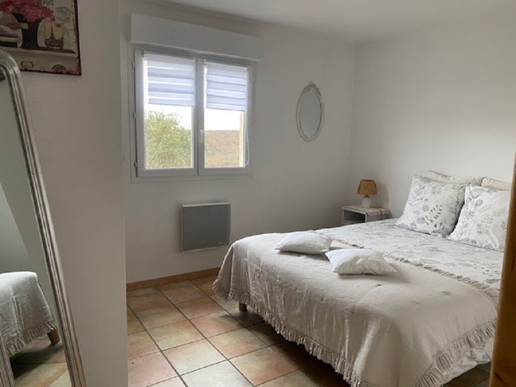 Une chambre à coucher avec un lit, une table de chevet, une fenêtre et un radiateur.