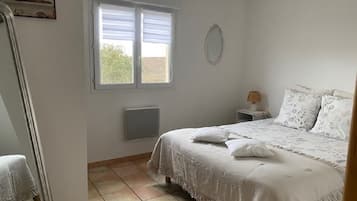 Une chambre à coucher avec un lit, une table de chevet, une fenêtre et un radiateur.