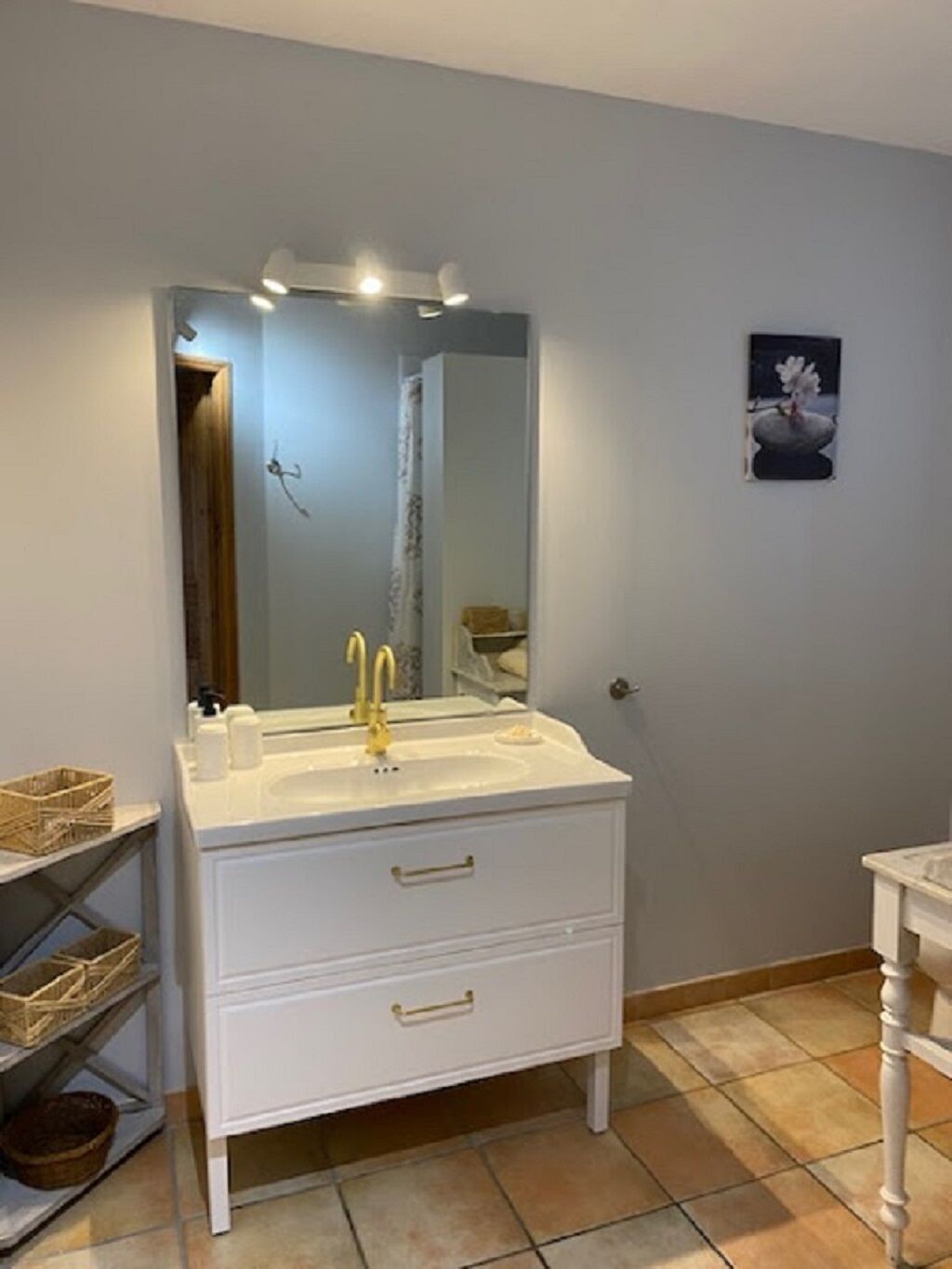 A bathroom with a white vanity, a mirror, and a sink.