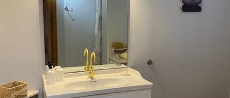A bathroom with a white vanity, a mirror, and a sink.