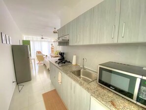 A modern kitchen with grey cabinets, a built-in microwave, and a stainless steel sink. - Modern Tropical, no 21, Cabarete Studio: Pools & BBQ (Cabarete)