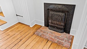 Un plancher en bois mène à une porte blanche dotée d’une poignée en métal noir.