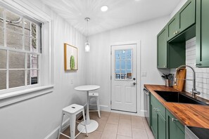 A compact kitchen with white walls, a wooden countertop, and green cabinets. - Quiet, walk to the stadiums, harbor, rooftop deck (Baltimore)
