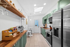 Eine moderne Küche mit Edelstahlkühlschrank, Holzregalen und einem Oberlicht.