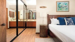 Ein Hotelzimmer mit einem großen Spiegel, einem Bett mit blau-weißen Kissen, einem Nachttisch mit einer Lampe und einem gerahmten Bild an der Wand.