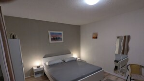 A bedroom with a bed, a nightstand, a mirror, a chair, and a refrigerator. - Quietly situated in the Lahn-Dill mountains (Bad Endbach)
