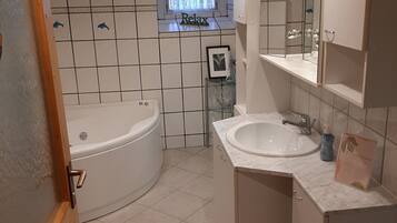 A modern bathroom with a freestanding bathtub, a vanity with a mirror, and a window with a 'Relax' sign.
