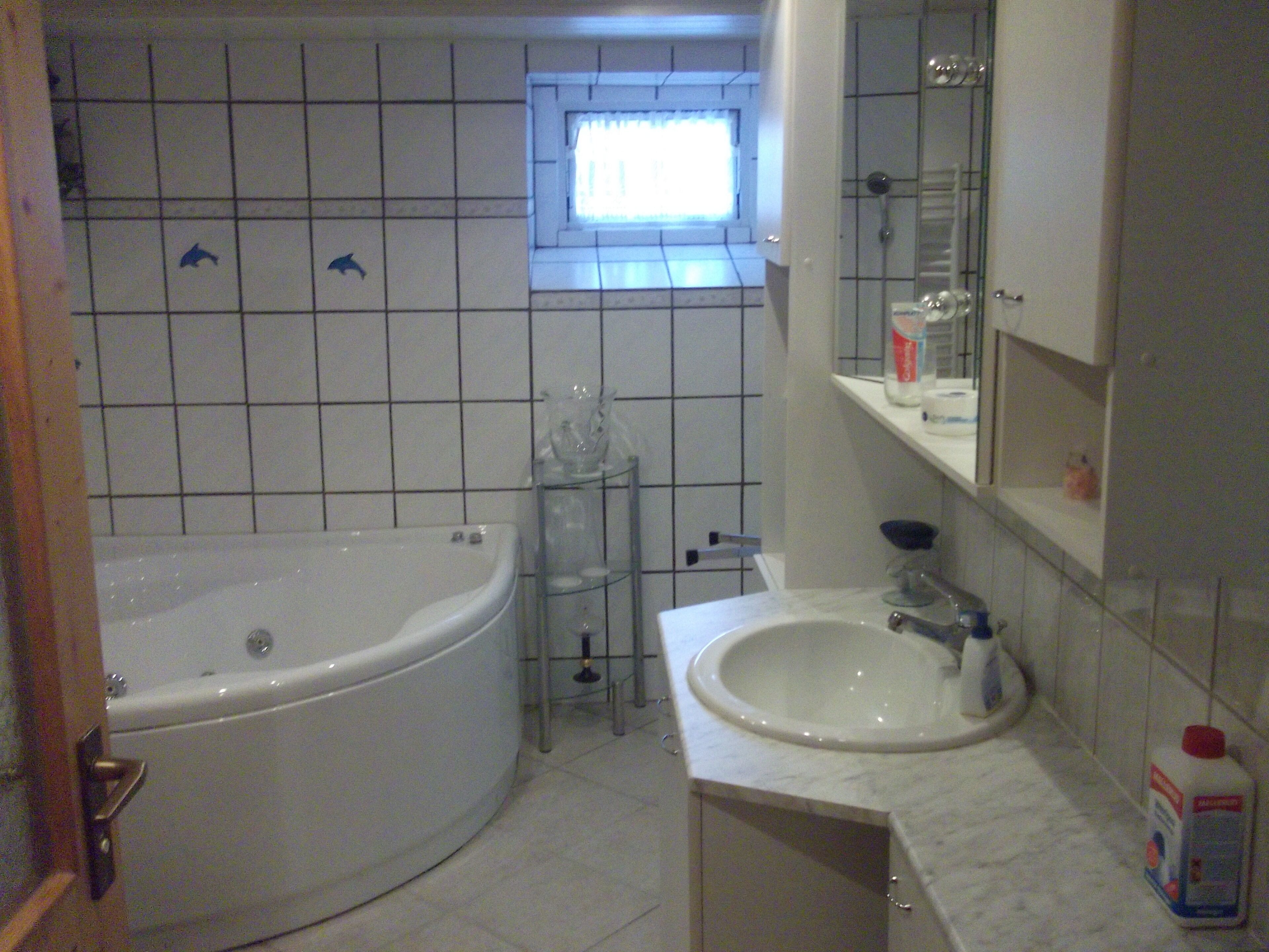 A bathroom with a bathtub, a sink, and a window.