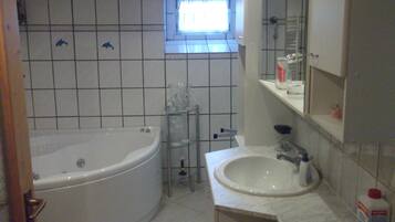 A bathroom with a bathtub, a sink, and a window.