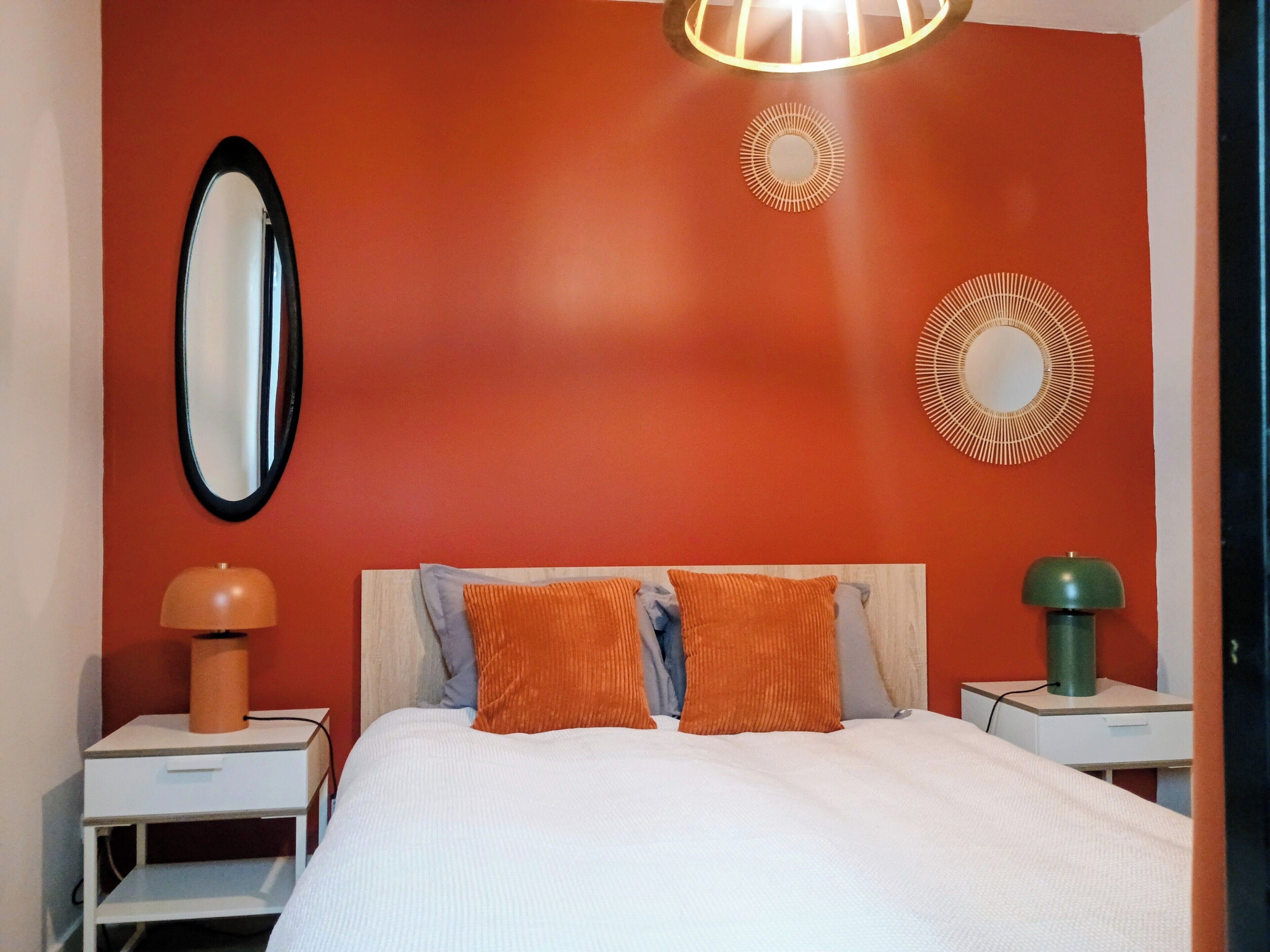 Quarto com cama, duas mesas de cabeceira, espelho e decoração na parede.