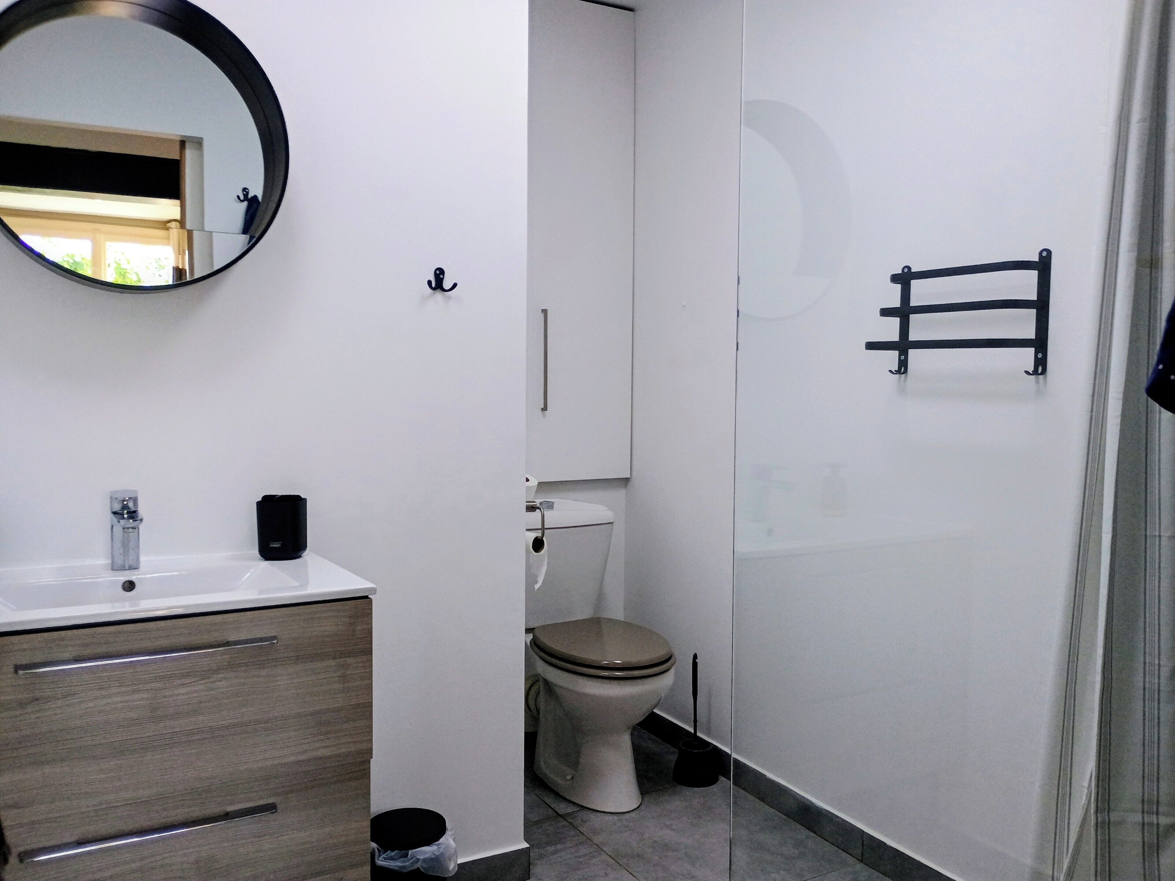 Ein Badezimmer mit Toilette, Waschbecken, Spiegel und Duschbereich.