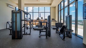 A gym with various exercise equipment, large windows, and a view of the sky. - Comfortable with pool and full gym (Cancún)
