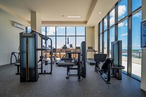 A gym with various exercise equipment, large windows, and a view of the sky. - Comfortable with pool and full gym (Cancún)