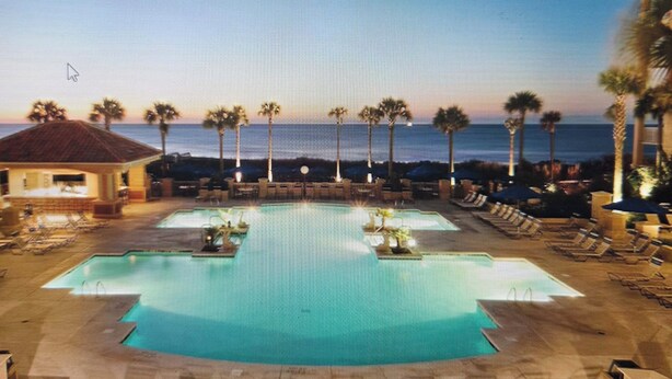 A resort pool area with multiple pools, lounge chairs, and palm trees. - Marriott OceanWatch 2-bedroom villa in Myrtle Beach, SC (Myrtle Beach)