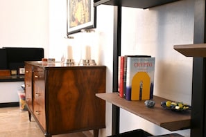 Un comò in legno con ripiano che contiene libri e una piccola ciotola con limoni.