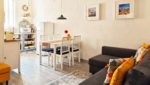 A living room with a sofa, a dining table with chairs, a kitchen area with a microwave, and a ceiling fan. - An exclusive, quiet home and the terrace of your dreams in the heart of Noto (Noto)