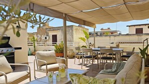 An outdoor patio with seating, a grill, and potted plants. - An exclusive, quiet home and the terrace of your dreams in the heart of Noto (Noto)