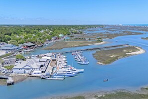 A marina with boats docked, a pier extending into the water, and buildings along the waterfront. - 5BR Luxury House- Steps to sand-Private Pool (Murrells Inlet)