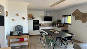 Una cucina moderna con zona pranzo, pavimento in legno e un'ampia finestra.