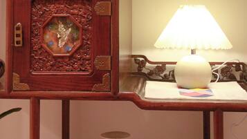A wooden shelf with a traditional Chinese vase, a small white teapot, and a lamp.