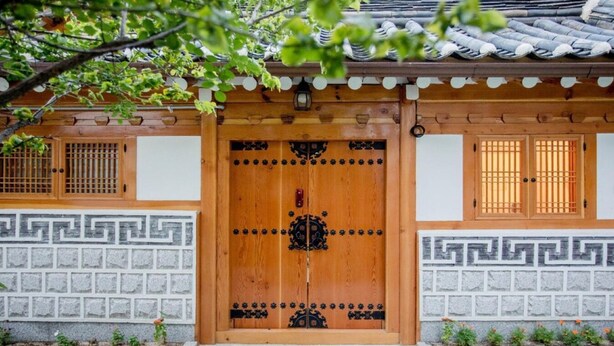 Un edificio tradicional de madera con una puerta central grande, diseños decorativos en las paredes y un techo de tejas.